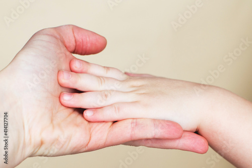 Close up of mothers hand holding babies hand Isolated on beige background.