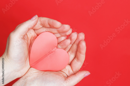 female hands hold a red heart on the palms isolated on a red background. Love  Wedding  Valentines day  8 March concept.