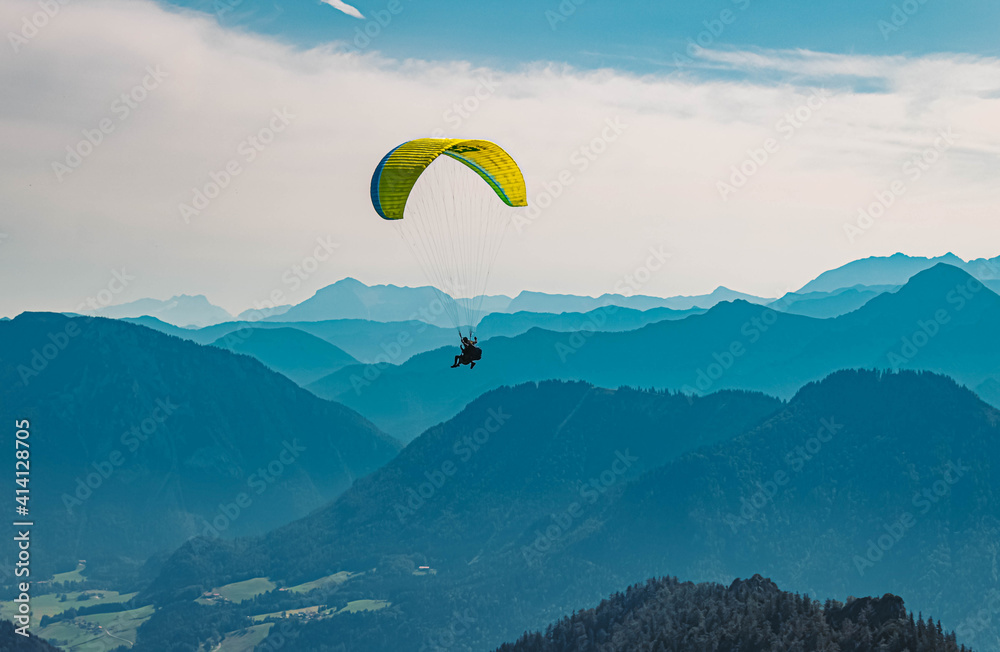 Beautiful alpine summer view with a paraglider and mountain silhouettes in the background at the famous Hochfelln summit, Bergen, Bavaria, Germany Beautiful alpine summer view with a paraglider and mountain silhouettes in the background at the famous Hochfelln summit, Bergen, Bavaria, Germany
