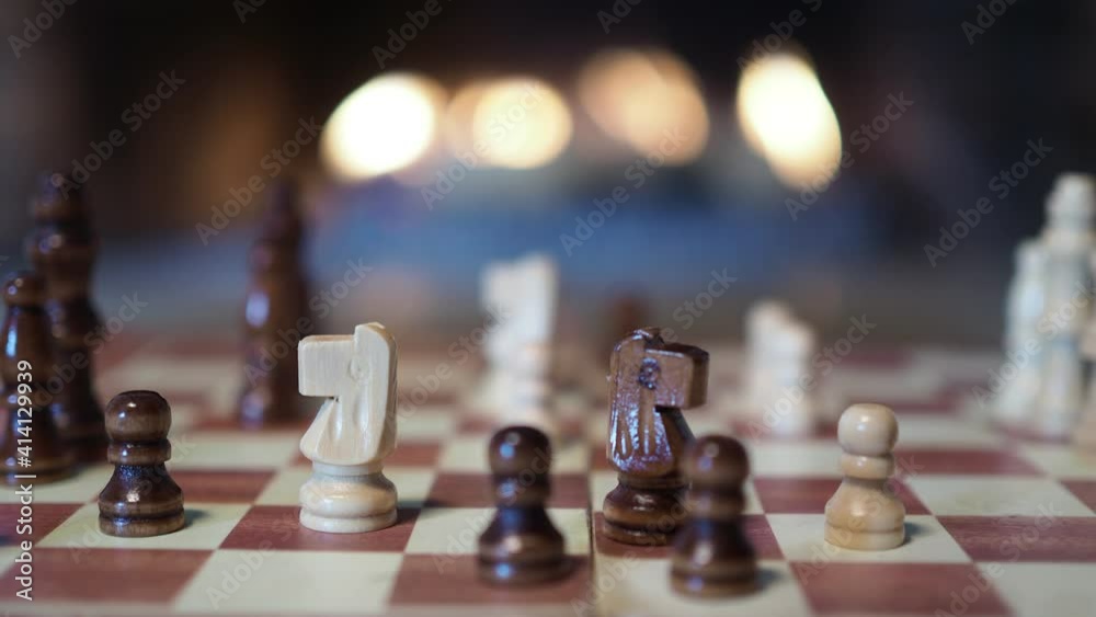 Chess. The hands of a child and an adult move the pieces on the chessboard against the background of the fireplace flame. Close-up shooting. Chess. The hands of a child and an adult move the pieces on the chessboard against the background of the fireplace flame. Close-up shooting.