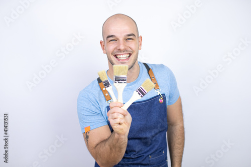 Obraz na plátně Young bald man wearing apron uniform over isolated white background holding pain