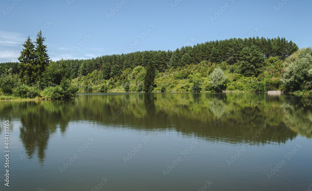 Landscape of calm lake in forest, reflections on water