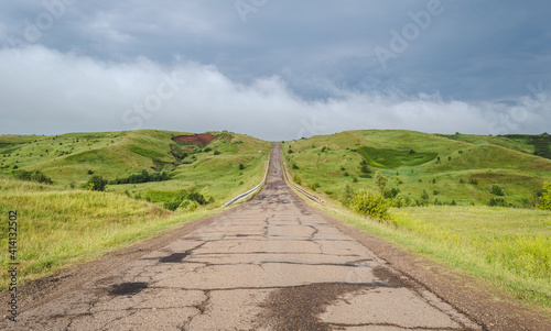 Long driveway in hills, storm landscape with clouds