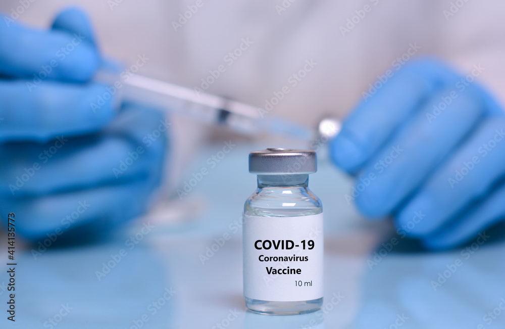 Coronavirus vaccine vial on the background of a doctor in medical gloves, a vial and a syringe. The concept of medicine, healthcare and science. Coronavirus vaccine vial on the background of a doctor in medical gloves, a vial and a syringe. The concept of medicine, healthcare and science.
