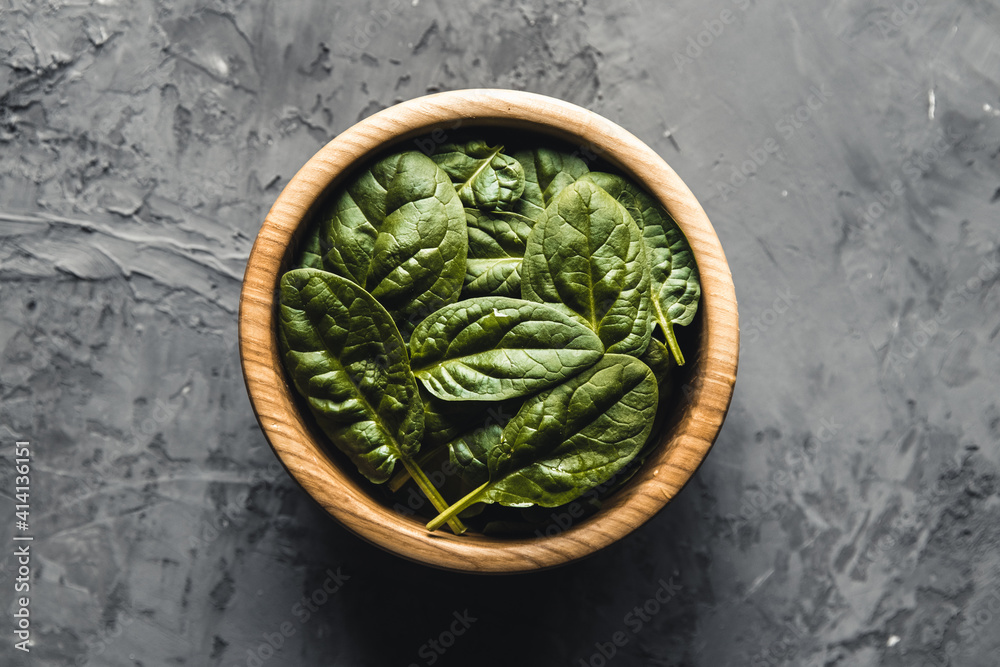 Baby spinach leaves in bowl on grey concrete backgroundClean eating, detox, diet food ingredient