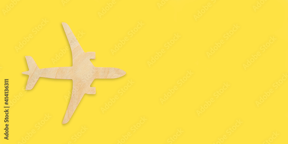 Wooden airplane model on a yellow background, toy jet. Flight, vacation, flight search, ticket booking, travel insurance, dreams, tourism, open border. Minimal design banner, flat lay, copy space