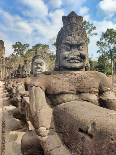 Stone sculptures on the bridge in Angkor. Unesco World Heritage Site. Siem Reap Province. Ancient ruins and trees. Cambodia. South-East Asia
