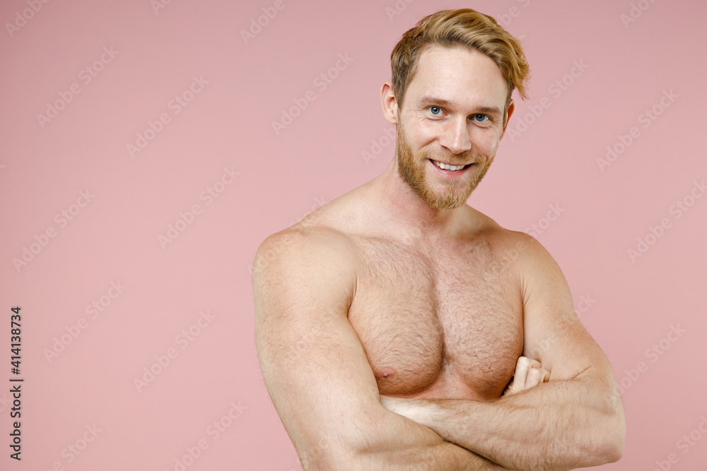 Fototapeta premium Smiling attractive bearded naked young man 20s years old perfect skin holding hands crossed isolated on pastel pink color background studio portrait. Skin care healthcare cosmetic procedures concept.