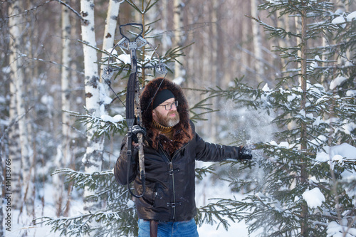 Fototapeta a man of European appearance in the winter forest shoots from a sports crossbow