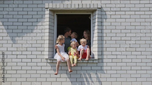 The concept of a large family. A friendly family hugs each other in the window of their house.