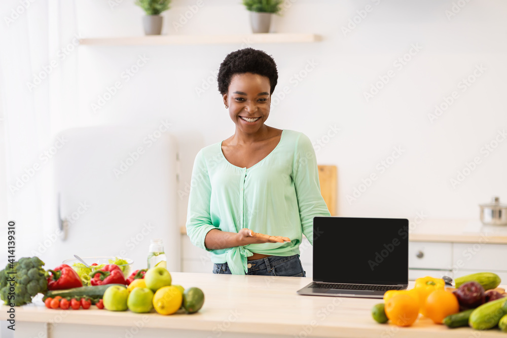 Black Woman Showing Laptop Screen Posing In Kitchen At Home