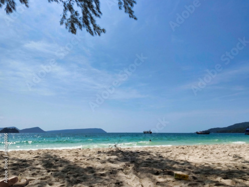 Fototapeta Naklejka Na Ścianę i Meble -  An empty beach with white sand and waves. Islands and boats in the distance. 4K Beach. Koh Rong island.  Cambodia. South-East Asia