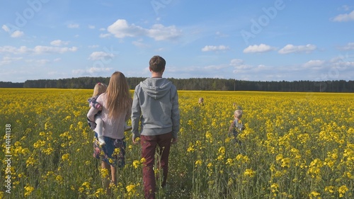 A happy family walks on a rapeseed field.