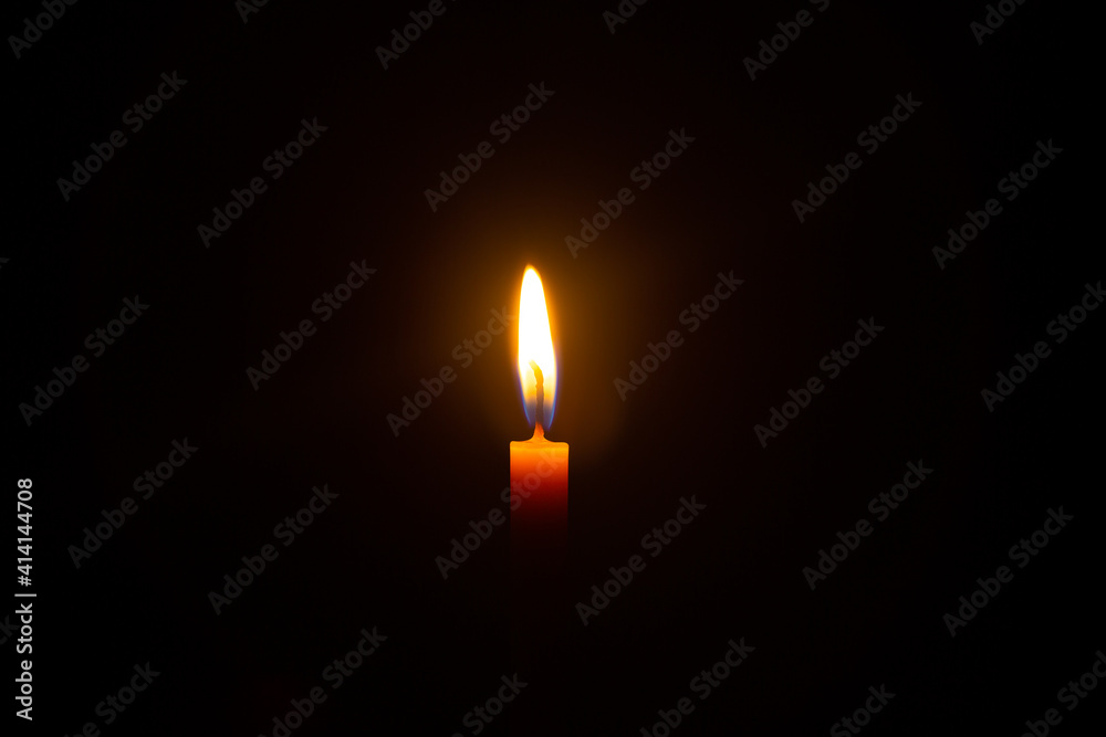 One light candle burning brightly in the black background