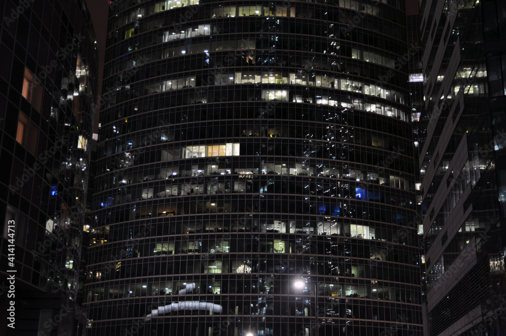 Facades of multi-storey office and residential buildings at night.