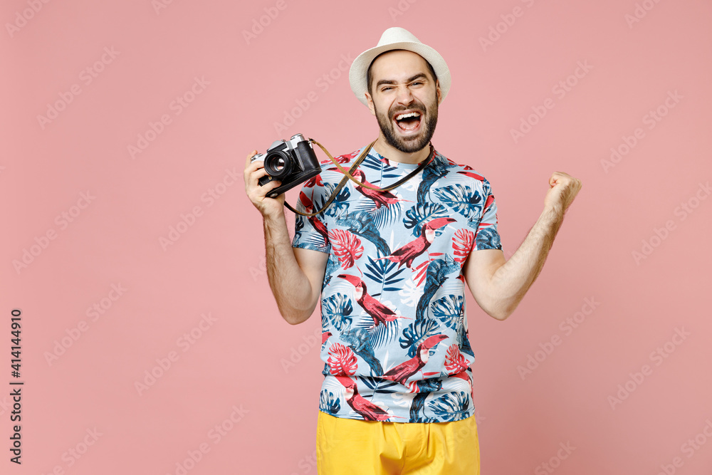 Happy young traveler tourist man in summer clothes hat hold retro vintage photo camera doing winner gesture isolated on pink background. Passenger traveling on weekends. Air flight journey concept. Happy young traveler tourist man in summer clothes hat hold retro vintage photo camera doing winner gesture isolated on pink background. Passenger traveling on weekends. Air flight journey concept.