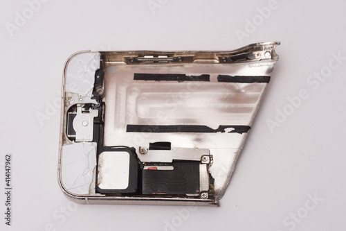 Broken electronic device, a piece of metal siver smartphone on white background
 photo