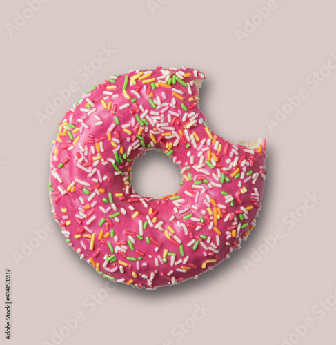Delicious glazed pink bite doughnut with sprinkles on gray  background