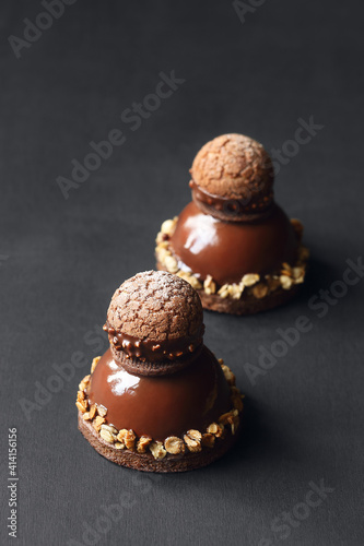 Contemporary Chocolate Mousse Cake with Craquelin Choux Pastry, covered with chocolate mirror glaze, on a dark background. photo