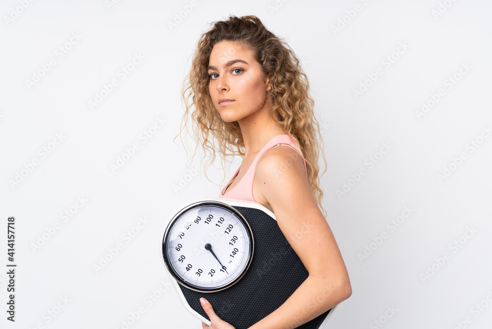 Young blonde woman with curly hair isolated on white background with weighing machine Young blonde woman with curly hair isolated on white background with weighing machine