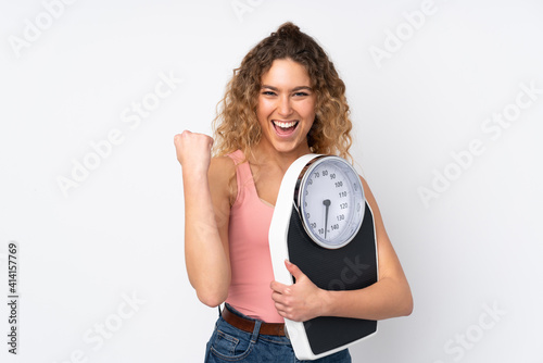 Fotografie Young blonde woman with curly hair isolated on white background with weighing ma