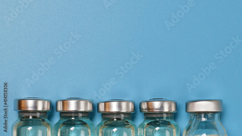 Coronavirus covid-19 experimental vaccine vials on a blue plate with copyspace in a laboratory