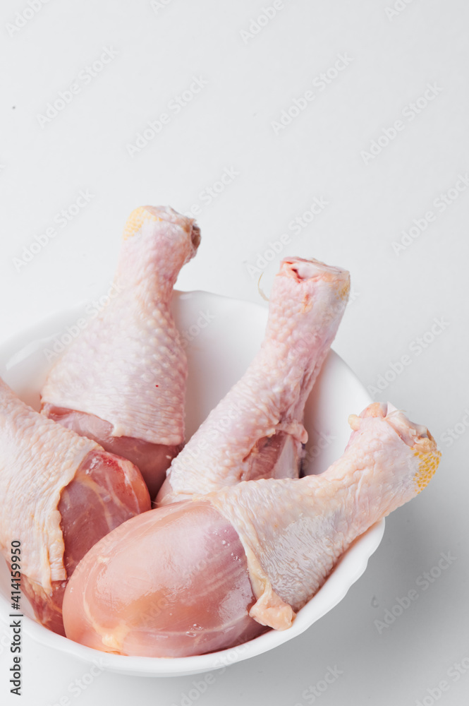 Raw chicken legs on a white plate isolated  on a white background. Close-up. Mockup
