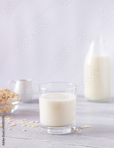 Vegetable oat milk in a glass cup on a light background. Healthy drinks, vegetarianism. Side view. Vertical photo