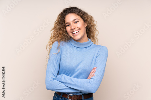 Картината върху платно Young blonde woman with curly hair wearing a turtleneck sweater isolated on beig