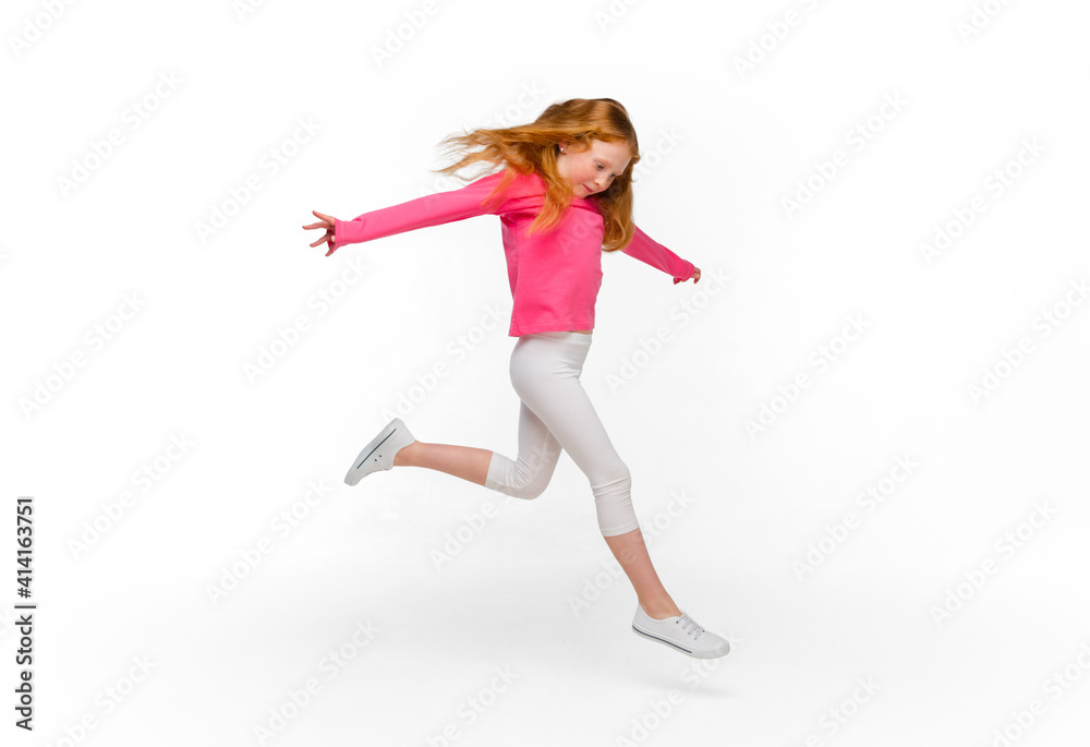 Smiling, jumping, running. Happy, smiley redhair girl isolated on white studio background with copyspace for ad. Looks happy, cheerful. Childhood, education, human emotions, facial expression concept.