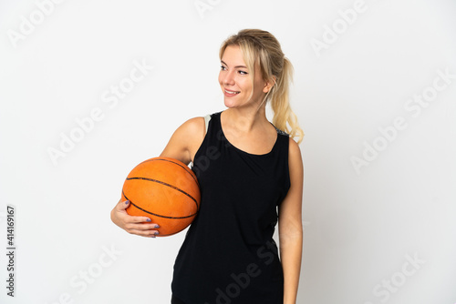 Young Russian woman playing basketball isolated on white background looking to the side and smiling