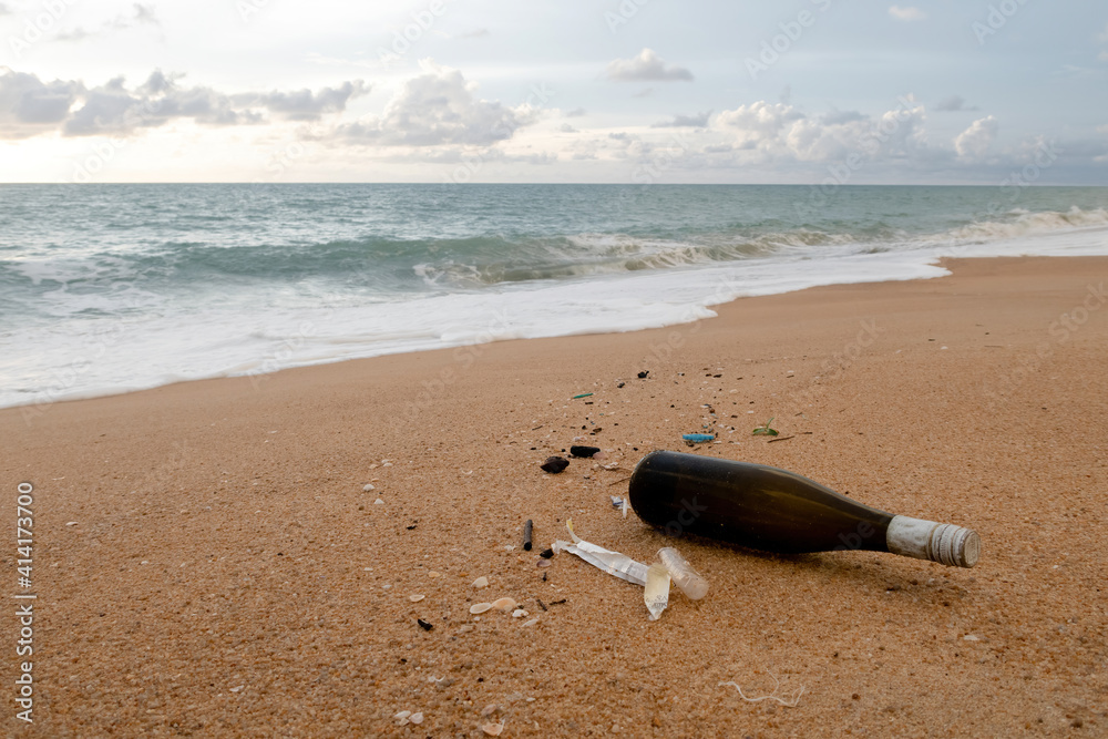 Concept of environmental issues, brown drink bottles and debris on the sand beach . Concept of environmental issues, brown drink bottles and debris on the sand beach .