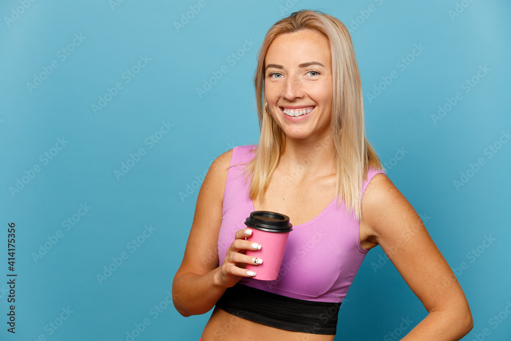 Portrait of cheerful fitness girl with pink coffee cup over blue background Portrait of cheerful fitness girl with pink coffee cup over blue background