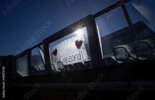 Stay healthy. Blijf gezond. Hearts. Text on frozen window. Winter. Frost. Sunlight on window. Julianadorp Northsea coast Netherlands. Backlight. photo