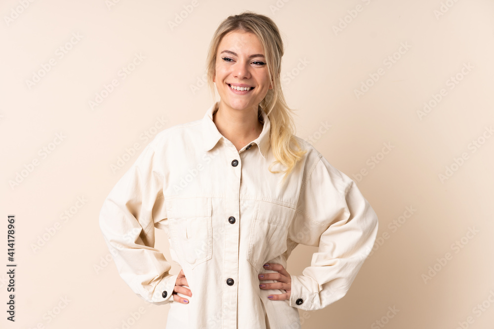 Blonde woman over isolated background posing with arms at hip and smiling Blonde woman over isolated background posing with arms at hip and smiling