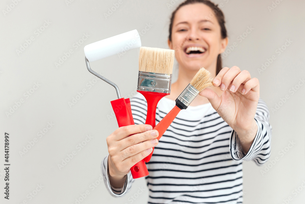 Young woman is painting the wall with paint brushes Young woman is painting the wall with paint brushes