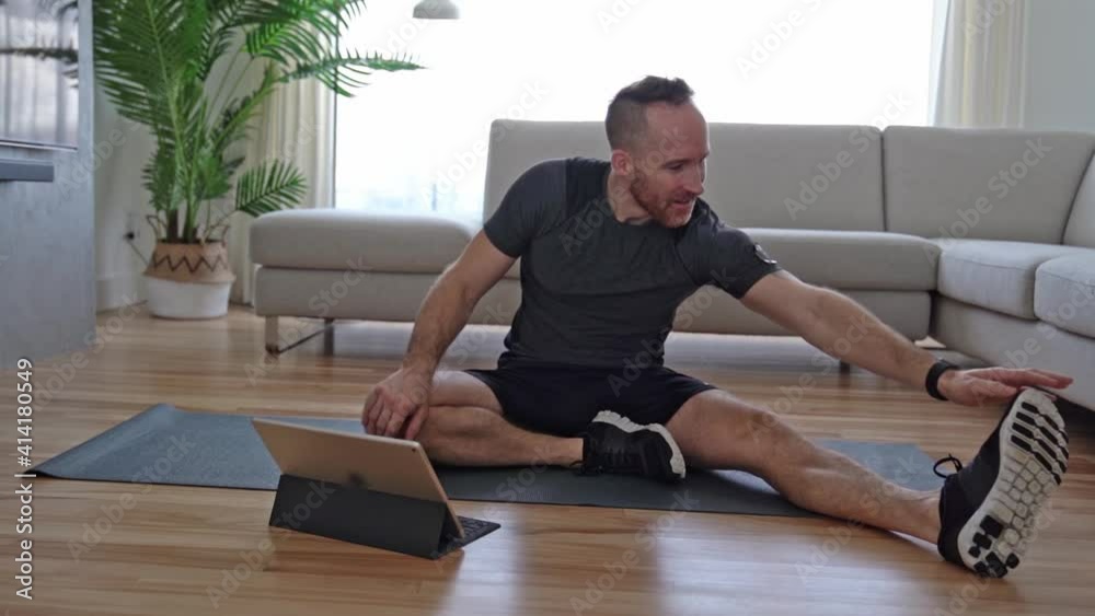 Athletic middle age man doing training at home with tablet. Athletic middle age man doing training at home with tablet.