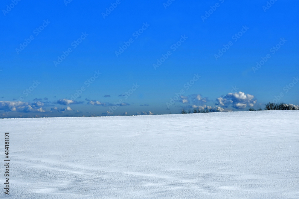 Je zur Hälfte eine mit Schnee bedeckte weiße Fläche vor tiefblauem Himmel