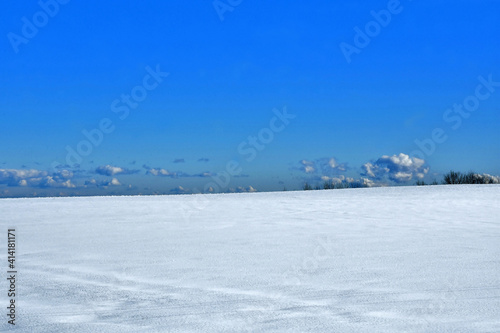 Je zur Hälfte eine mit Schnee bedeckte weiße Fläche vor tiefblauem Himmel