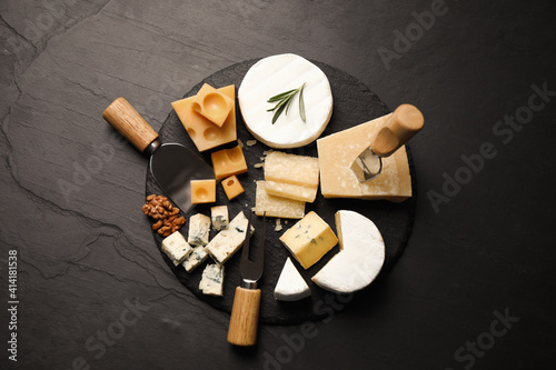 Φωτογραφία Cheese platter with specialized knives and fork on black table, flat lay