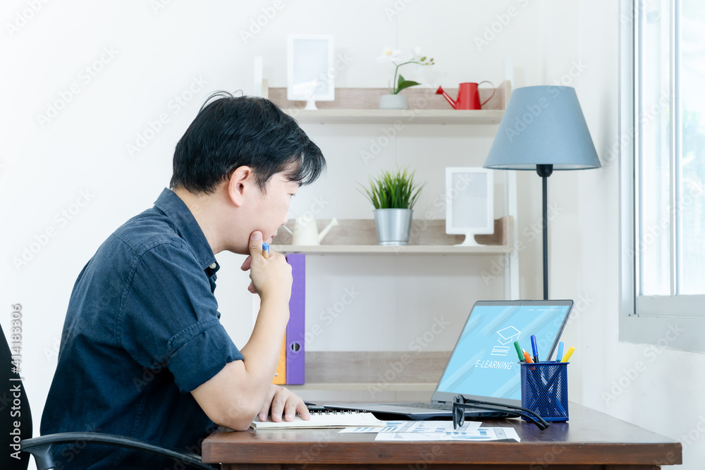 E learning. Casual business man writing on notebook and working on laptop computer in home. Man studying online course via laptop and lecture on notepad. E learning. Casual business man writing on notebook and working on laptop computer in home. Man studying online course via laptop and lecture on notepad.