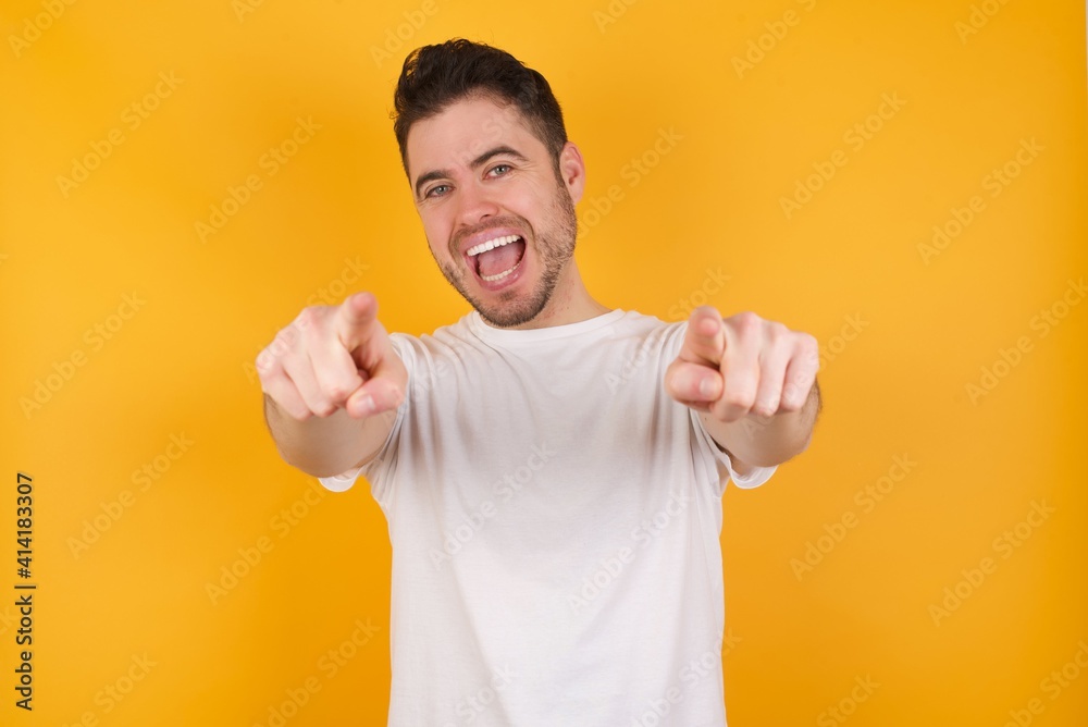 Close-up portrait of surprised young handsome Caucasian man holding a salad bowl against yellow wall pointing with two fingers to the camera saying: I choose you!, looking up with open mouth. Close-up portrait of surprised young handsome Caucasian man holding a salad bowl against yellow wall pointing with two fingers to the camera saying: I choose you!, looking up with open mouth.