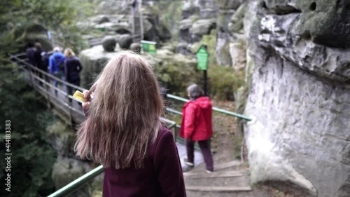 A young girl is walking along a mountain tourist trail. Saxon Switzerland National Park. Geological region. Unique mountainous landscape. National Park of Germany. Huge rocky massif Bastei 