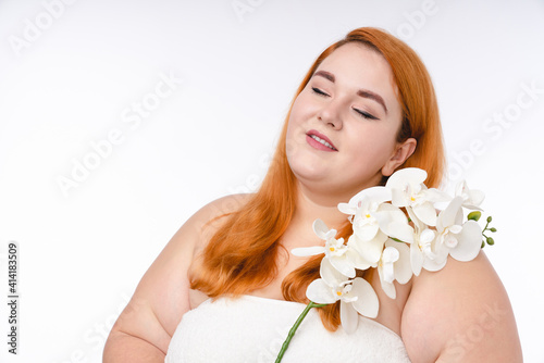 Beautiful young plump woman in spa towel with flower isolated over white background