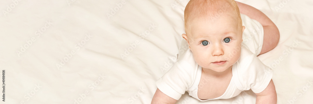 Cute small boy lying at bed. Childhood concept. Light background. Serious child. Copyspace. Stay home. Mockup. Horizontal banner. White clothes Cute small boy lying at bed. Childhood concept. Light background. Serious child. Copyspace. Stay home. Mockup. Horizontal banner. White clothes