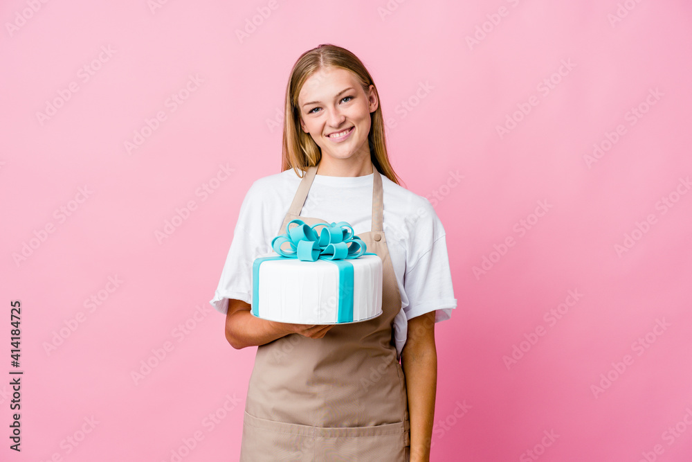 Young russian baker woman holding a delicious cake happy, smiling and cheerful. Young russian baker woman holding a delicious cake happy, smiling and cheerful.