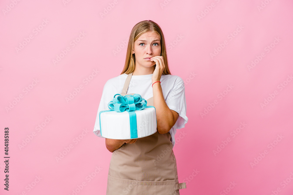Young russian baker woman holding a delicious cake biting fingernails, nervous and very anxious. Young russian baker woman holding a delicious cake biting fingernails, nervous and very anxious.