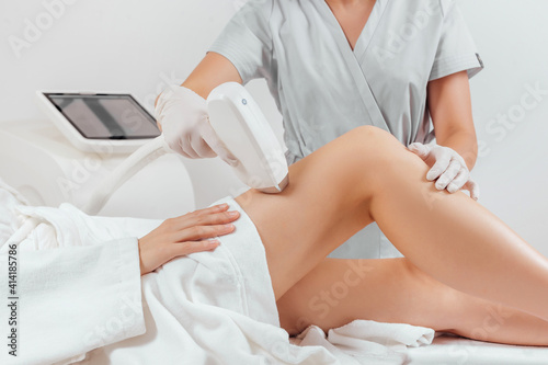 Young woman making body hair removal laser depilation in beauty center 