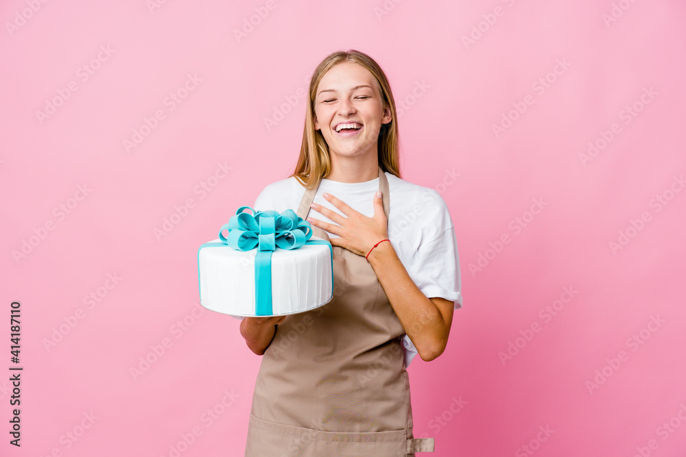 Young russian baker woman holding a delicious cake laughs out loudly keeping hand on chest. Young russian baker woman holding a delicious cake laughs out loudly keeping hand on chest.
