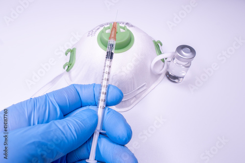 Medical bottle  vials  syringes and face mask on blue background with copy space. Vaccination session and immunity improvement.